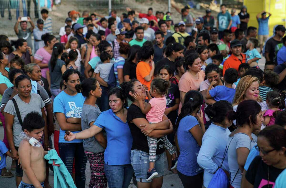 En esta imagen de archivo del 30 de agosto de 2019, migrantes, muchos de ellos devueltos a México por la política migratoria del entonces presidente estadounidense Donald Trump, hacen fila para recibir alimentos en un campamento en el puente internacional, en Matamoros, México.