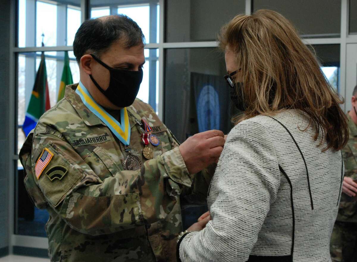 New York Army National Guard Lt. Col. Michael Tagliafierro pins a Family Recognition Award pin on his wife Maureen during his retirement ceremony.