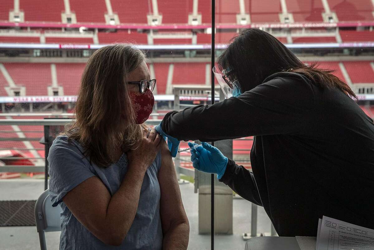 Clinical nurse Lynette Ancheta, right, injects Lynda Barbieri's arm with the Pfizer COVID-19 vaccine at Levi’s Stadium in Santa Clara on Feb. 9, 2021. Santa Clara County advanced Tuesday into the yellow tier, the least restrictive level of California’s color-coded pandemic reopening system.