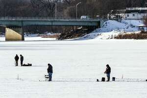 Taking advantage of an extended period of low temperatures, these people set up areas to fish on the Mohawk River across from the Stockade in Schenectady, N.Y. on Saturday, Feb. 13, and Sunday, Feb. 14, 2021. The fishing continued on Sunday. In the background are the New York State Route 50 bridge and the Glen Sanders Mansion.