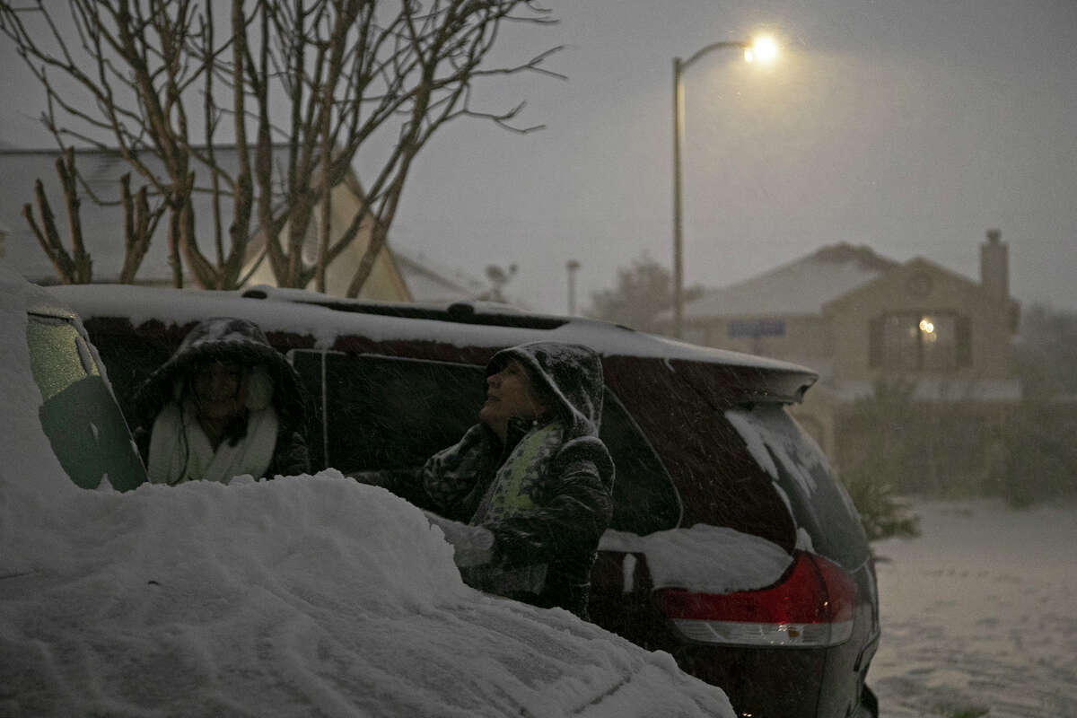 Carmen Rodriguez, 12, attempts to make a snow person with her mother, Georgina Rodriguez, late Sunday night, Feb. 14, 2021, in San Antonio.