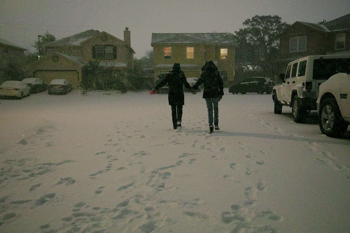 Georgina Rodriguez and her daughter, Carmen Rodriguez, 12, walk to a neighbor's home late Sunday night, Feb. 14, 2021, in San Antonio.