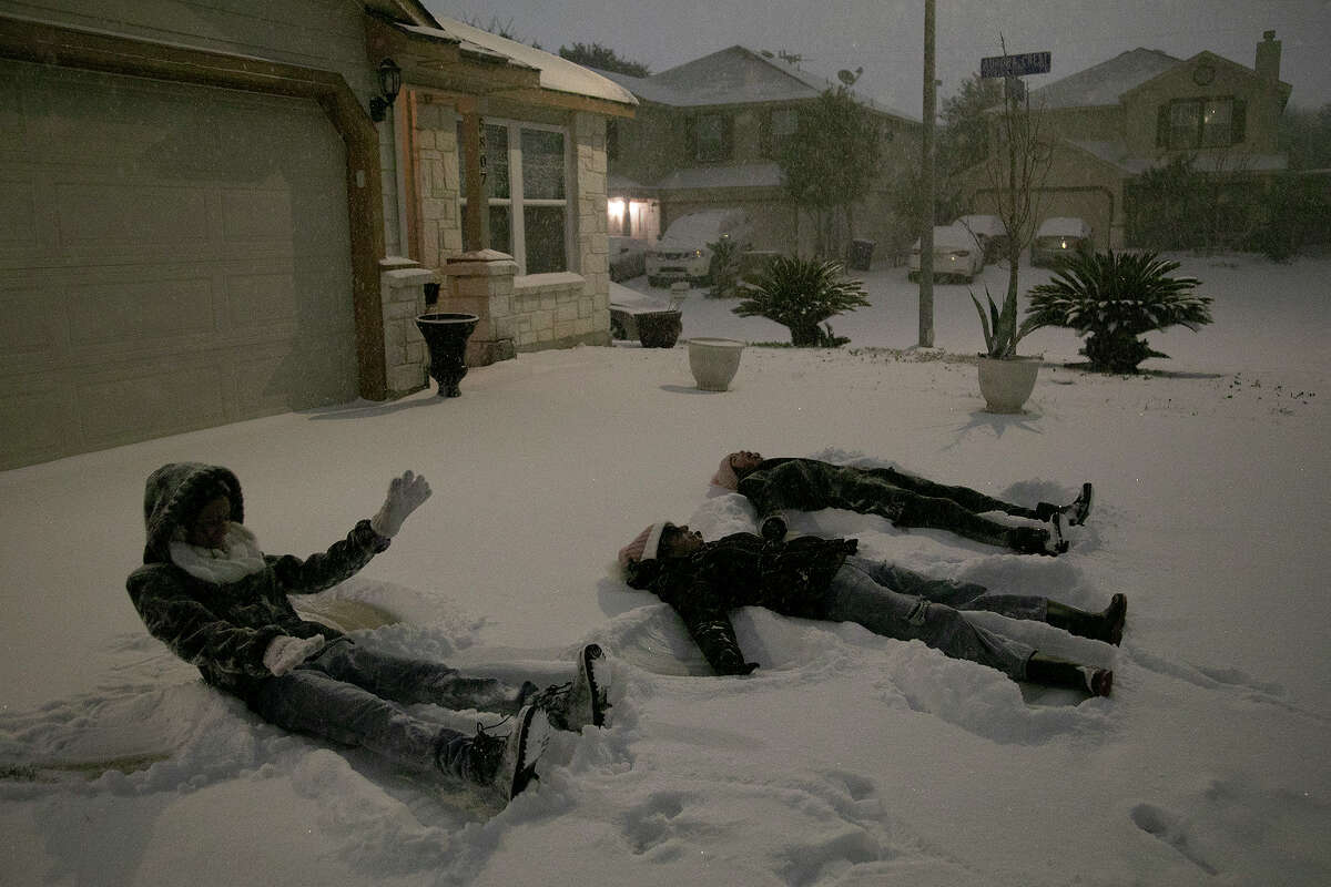Carmen Rodriguez, 12, from left, her sister, Georgina Rodriguez, 13, and Gaby Gonzales, 13, make snow angels in their neighbor's driveway late Sunday night, Feb. 14, 2021, in San Antonio.