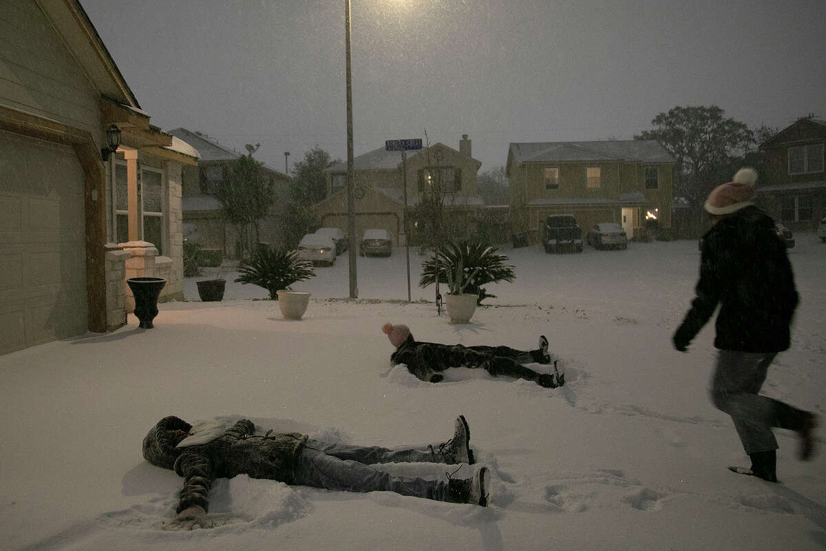 Georgina Rodriguez, 13, runs to make snow angels with her sister, Carmen Rodriguez, 12, left, and Gaby Gonzales, 13, late Sunday night, Feb. 14, 2021, in San Antonio.