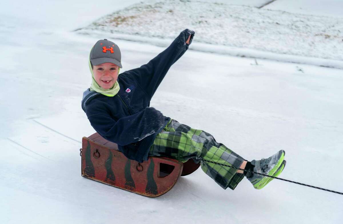 Neighbors play in the snow covered streets in the Westbury neighborhood, Monday, Feb. 15, 2021, in Houston.