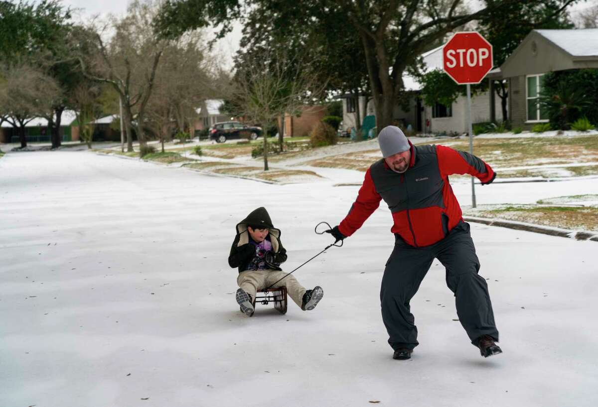 Neighbors play in the snow covered streets in the Westbury neighborhood, Monday, Feb. 15, 2021, in Houston.