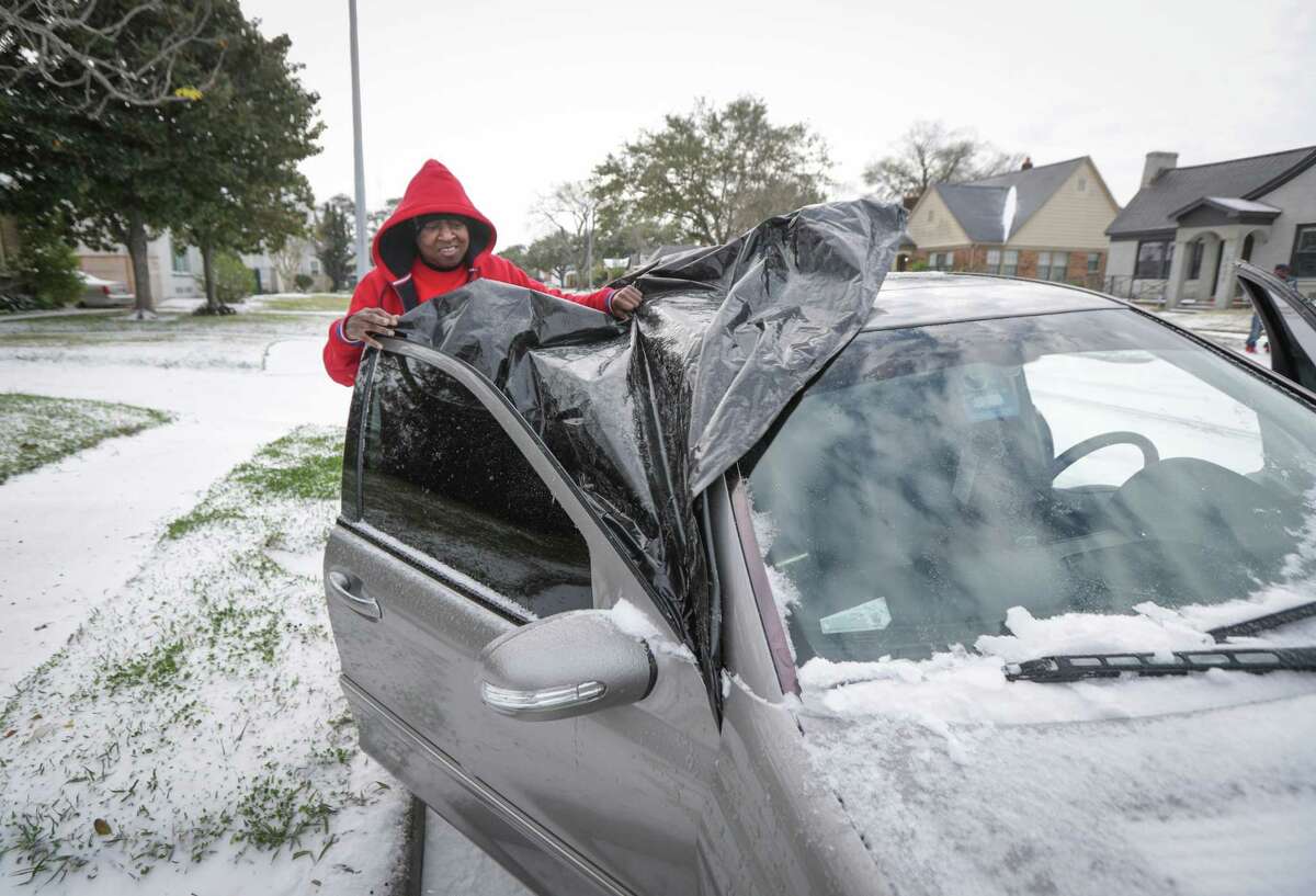 Jeranda Flowers removes plastic sheeting that covered her windshield of her car Monday, Feb. 15, 2021, in Houston.