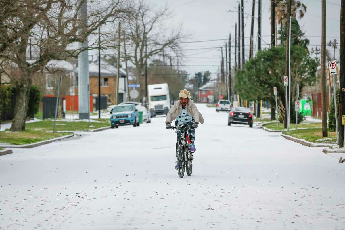 A man who said 'its too cold to stop' rides his bicycle on Delano near Rosewood Monday, Feb. 15, 2021, in Houston.