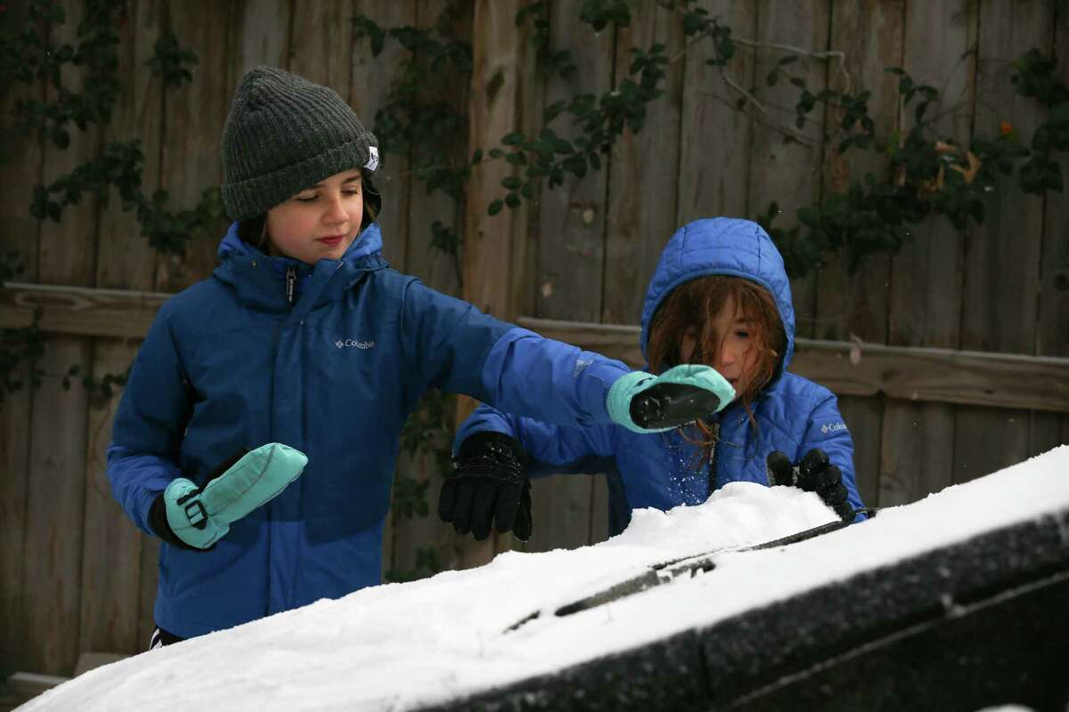 Siblings Phineas and Javier Carnell Simon play with snow on their parents car Monday, Feb. 15, 2021, at Montrose in Houston.