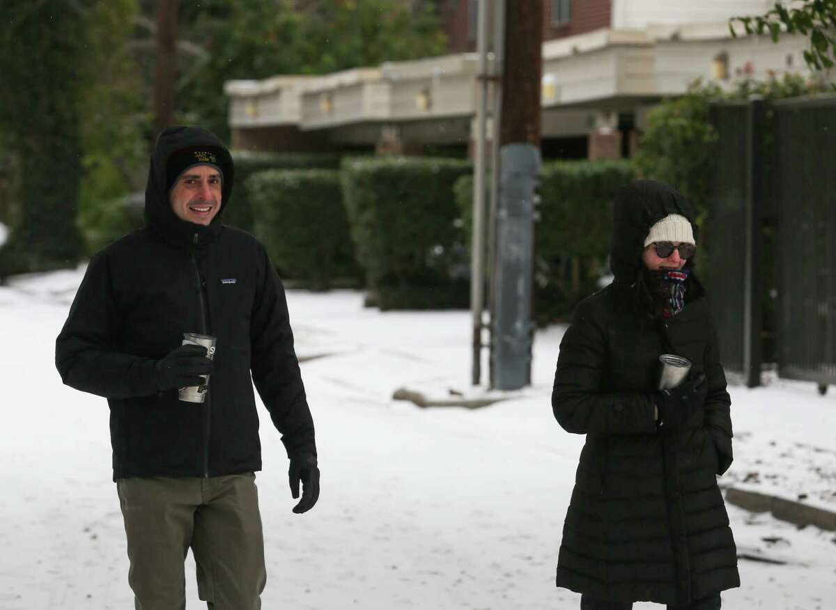 People walk around their neighborhood to check out snow Monday, Feb. 15, 2021, at Montrose in Houston.