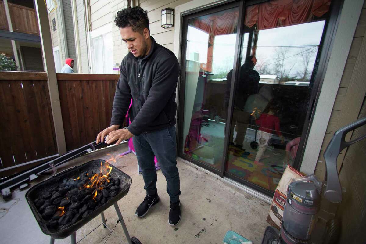 Kevin Morazan warms his hands after lightning his charcoal grill to cook after losing power due to rolling blackouts following an overnight snowfall in the Greenspoint area Monday, Feb. 15, 2021 in Houston. Temperatures plunged into the teens Monday with light snow and freezing rain. The stove in his apartment is electric.