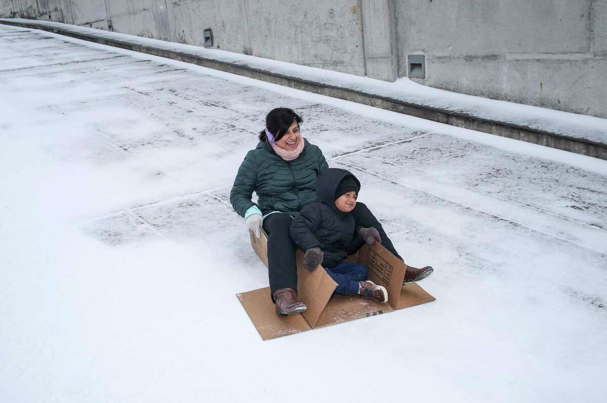 Toral Shah and her son Zavian, 3, slide down the ramp of a parking garage as a winter storm hits Houston on Monday, Feb. 15, 2021, at Carnegie Vanguard High School in Houston.
