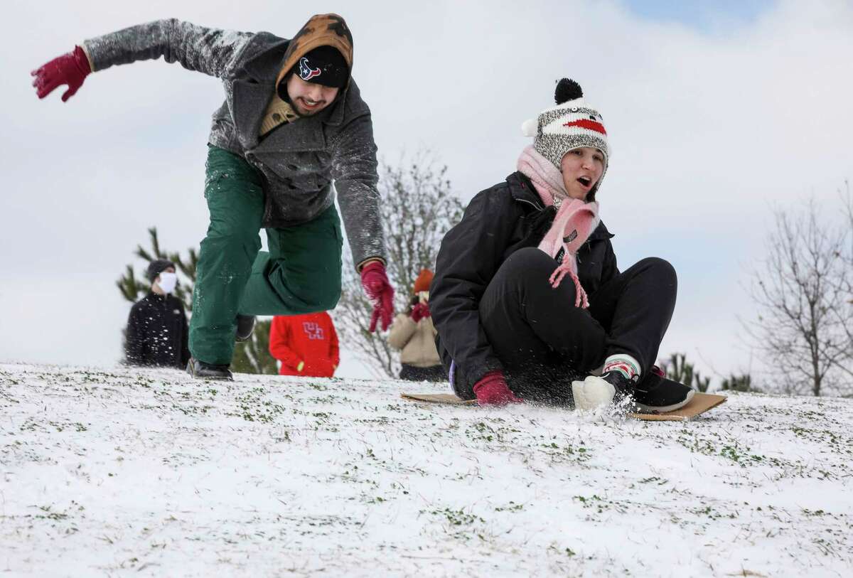 Jordan Martinez pushes Kendall Banasiak down a snow-covered hill as a winter storm hits Houston on Monday, Feb. 15, 2021, at Buffalo Bayou Park in Houston.