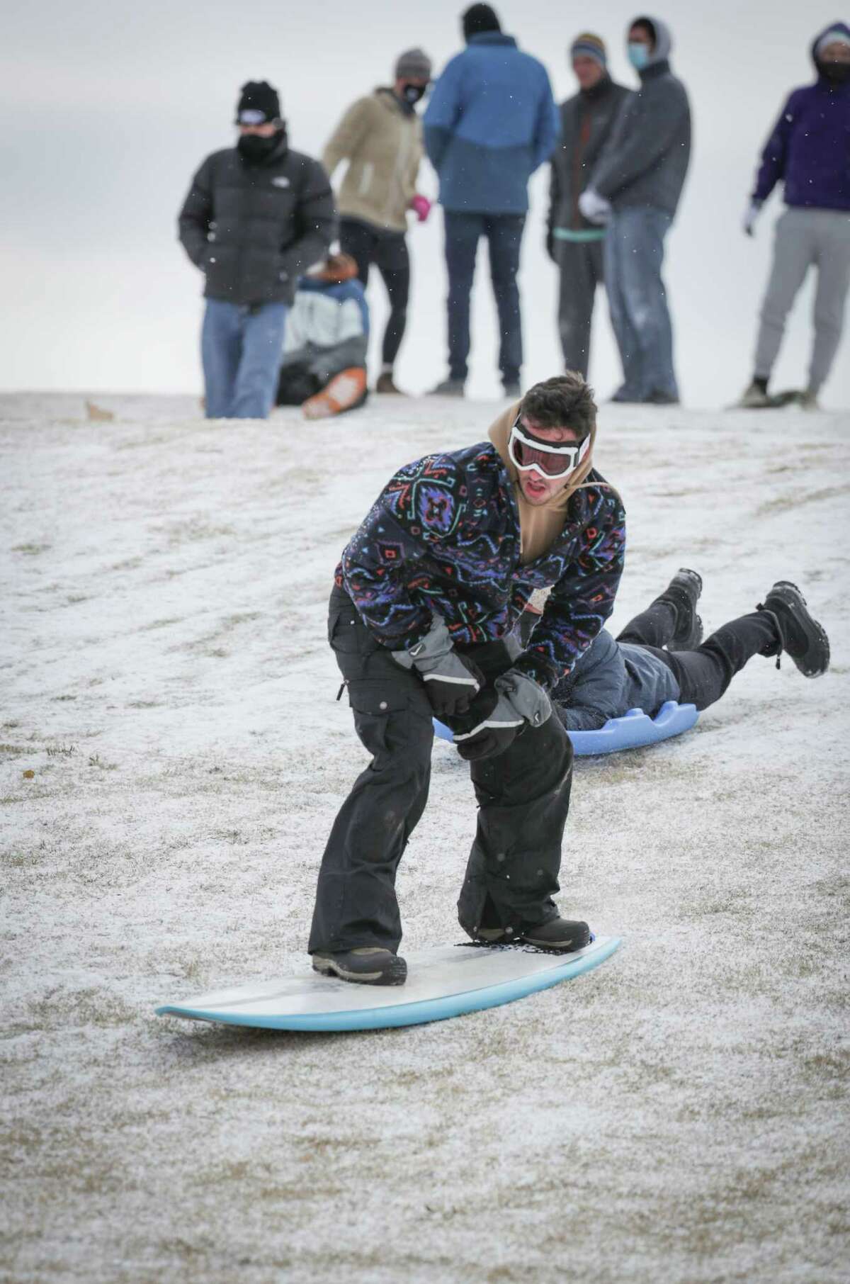 Gabe Navon uses a surf board to sled on the Miller Outdoor Theatre hill Monday, Feb. 15, 2021, in Houston.