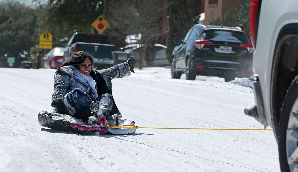 Daisy Gomez, 24, rides a deflated tube down South Ellison Drive in the Heritage neighborhood, Monday, Feb. 15, 2021.