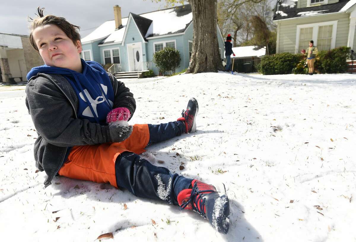 Lucas Trahan works on making a snowball from the layer of icy snow in his yard while playing outside with family and friends Monday. Photo taken Monday, February 15, 2021 Kim Brent/The Enterprise