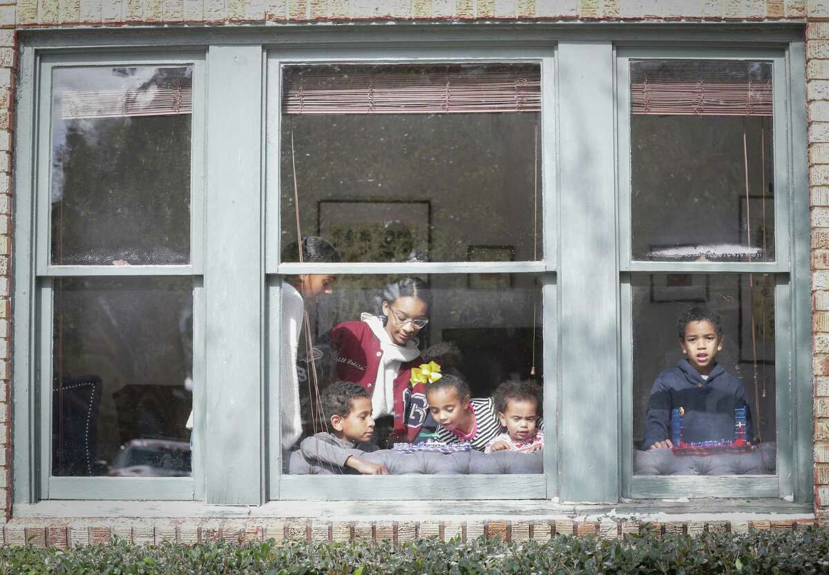 Ava Bocock (l-r), Richard Bocock, Elle Lewis, Catherine Bocock, Claire and Gregory Bocock stay warm playing in the sunlight of their front window during a power outage in Third Ward Monday, Feb. 15, 2021, in Houston.