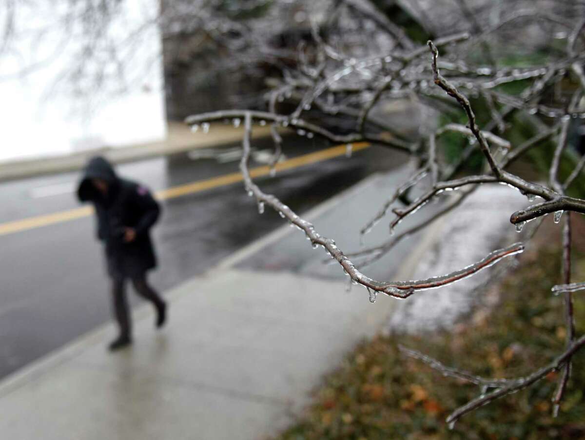 A file photo of an individual walking by an icy tree in Greenwich, Conn. Freezing rain is transitioning over to just rain Tuesday, Feb. 16, 2021.