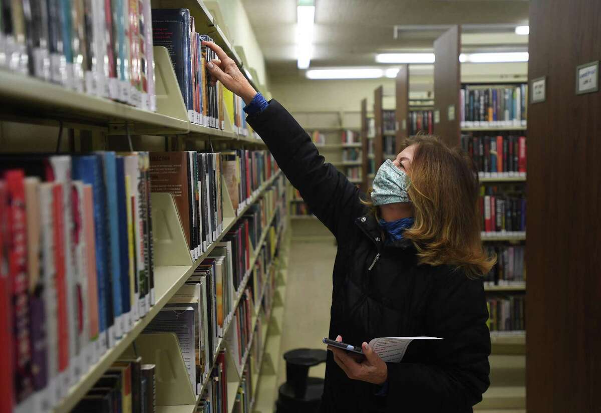 Juliann Vaughan, of Shelton, picks out a book after being the first customer through the doors during the reopening of the Plumb Memorial Library on Tuesday.