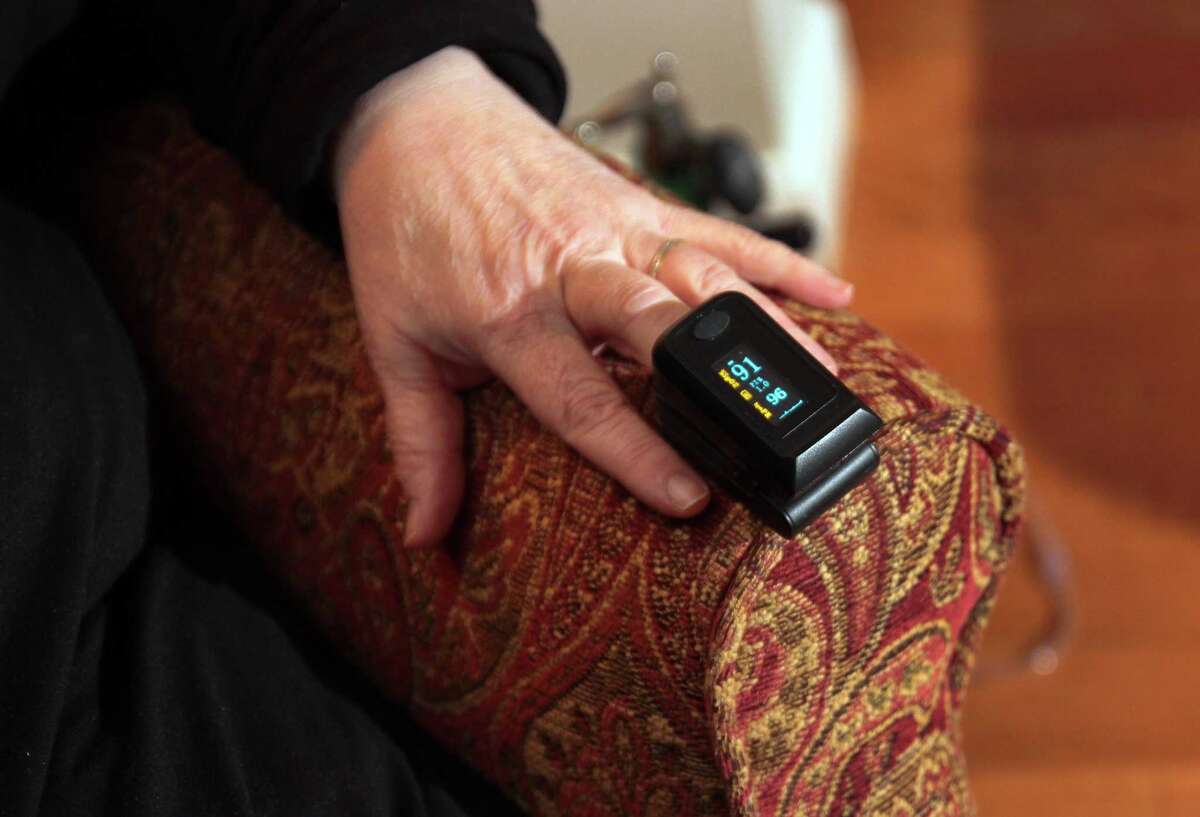 Joan Stokes takes an oxygen reading in her home.