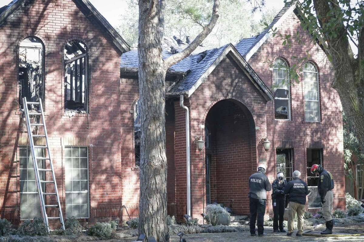 A medical examiner along with other investigators talk in front of a home where a grandmother and her three elementary-age grandchildren died Tuesday, Feb. 16, 2021, in Sugar Land.