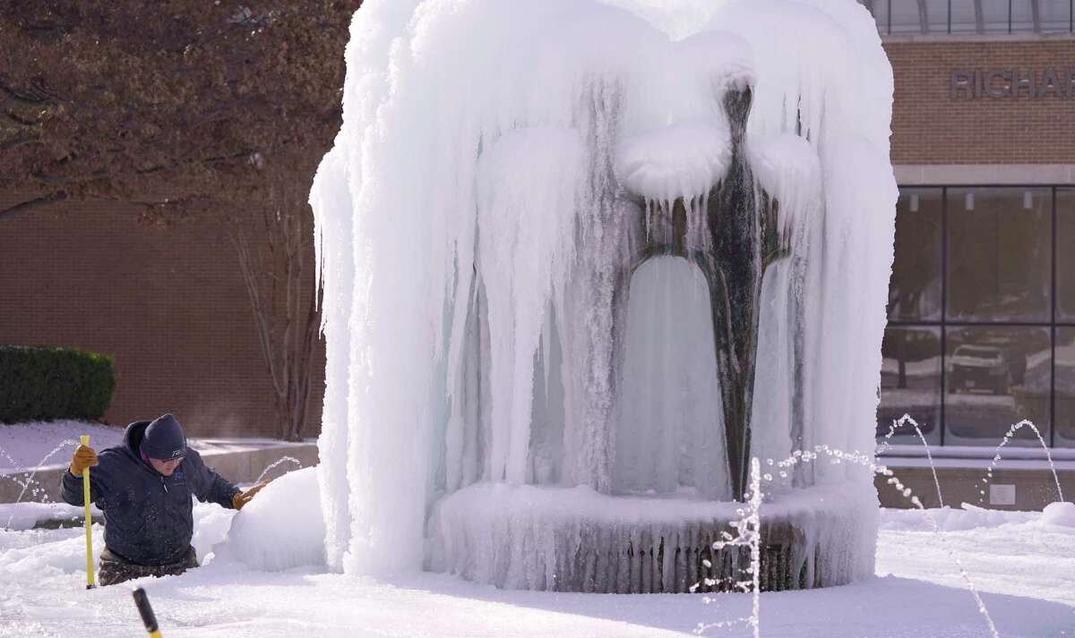 City of Richardson worker Kaleb Love works to clear ice from a water fountain Tuesday, Feb. 16, 2021, in Richardson, Texas. Temperatures dropped into the single digits as snow shut down air travel and grocery stores.