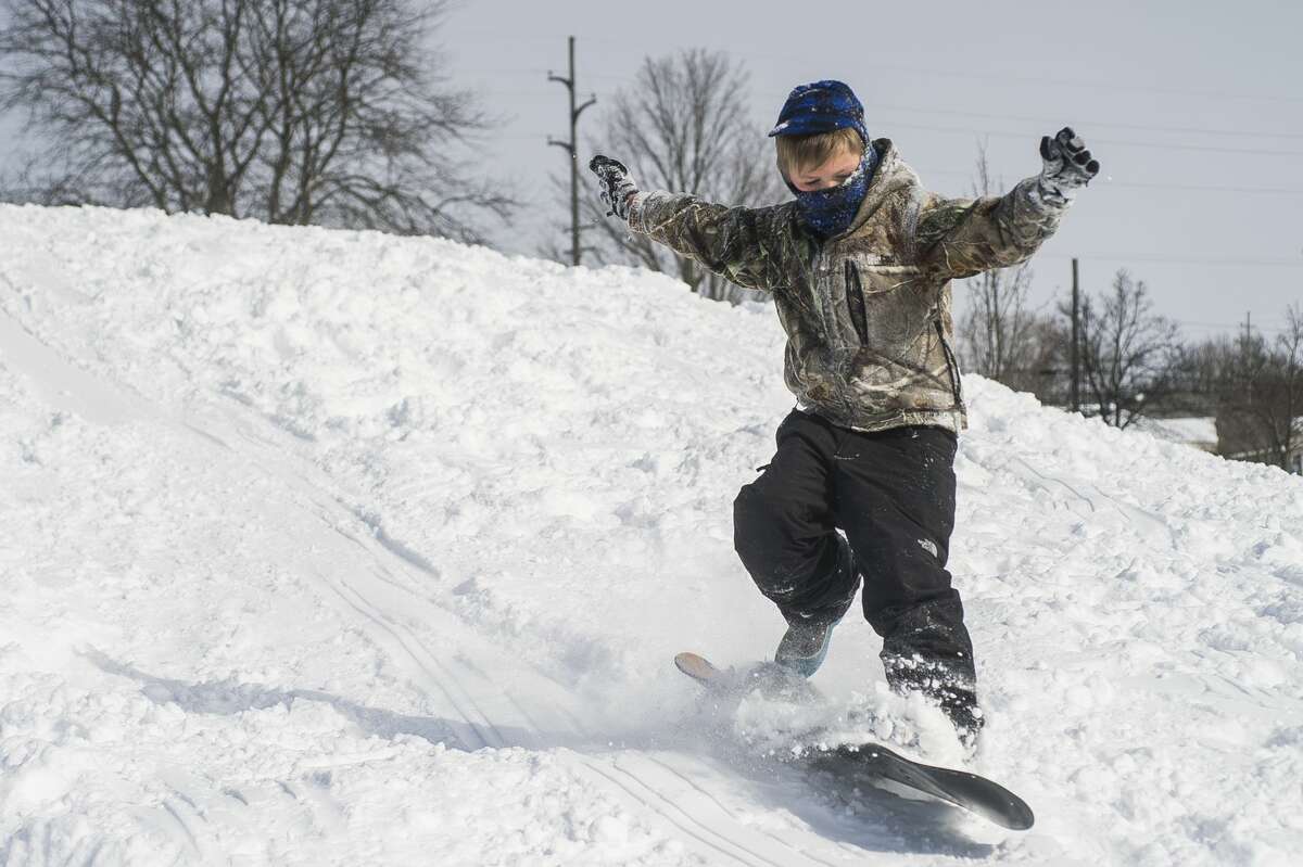 William Stockton, 7, goes sledding and snowboarding during a snow day for Midland Public Schools Tuesday, Feb. 16, 2021 at Plymouth Park in Midland. (Katy Kildee/kkildee@mdn.net)
