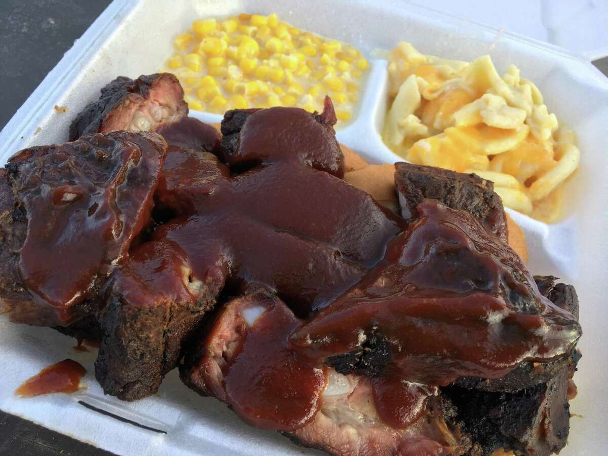 A plate of rib tips from The Purple Pig BBQ with sides of creamed corn and mac and cheese.