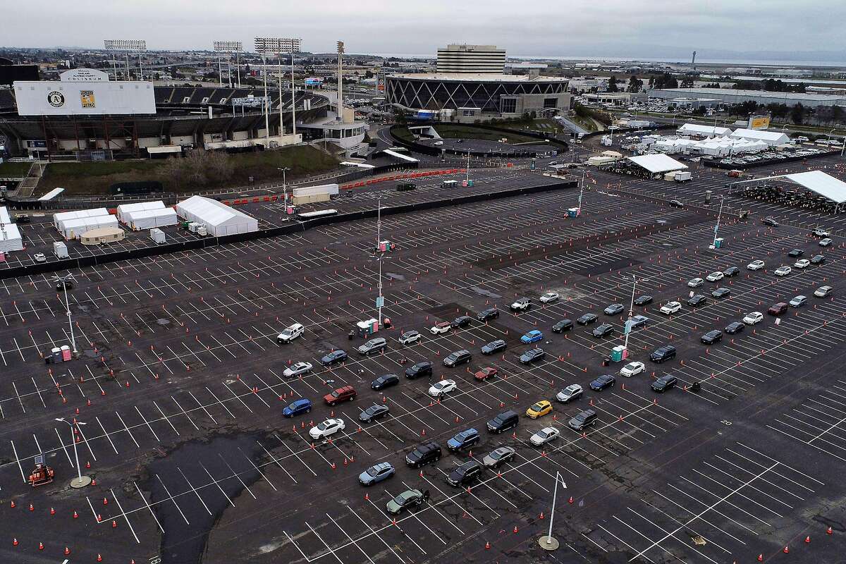 Recipients wait in an observation area in their cars after receiving coronavirus vaccines at the Oakland Coliseum.