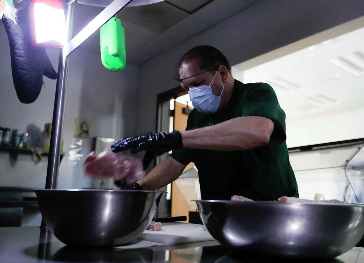 Tom Tucker helps prepare dinner in the dark after the Salvation Army’s shelter lost power, Tuesday, Feb. 16, 2021, in Conroe.
