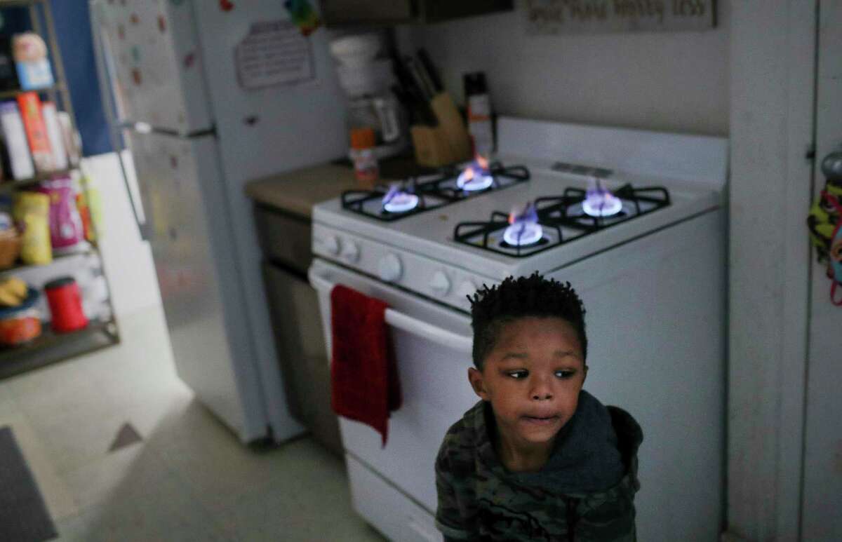 Kaiden Antoine, 3, stands by the stove, his family's only source of heat since their power has been out since yesterday, Tuesday, Feb. 16, 2021, at Cuney Homes in Houston.