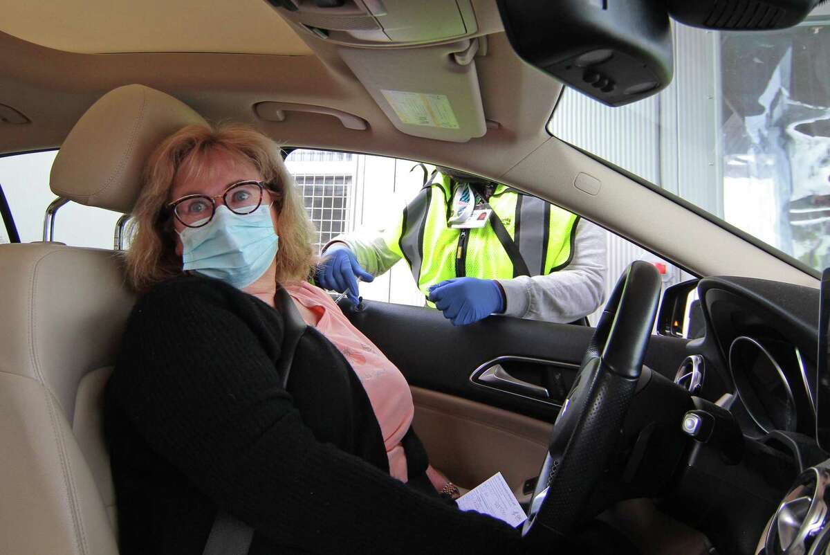 Gretchen Lupinacci, of Greenwich receives the Pfizer vaccine shot during Community Health Center's mass drive-through COVID-19 vaccination clinic held at the parking lot of Lord & Taylor in Stamford, Conn., on Wednesday Feb. 3, 2021.