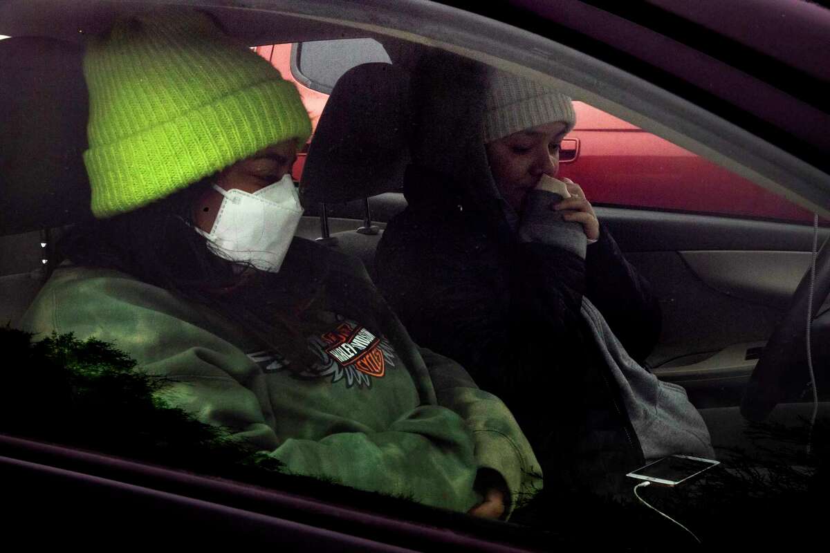 Victoria Garcia, left, and Laura Rosales sit in their car during a power outage to stay warm and charge their phones. Is our electrical grid prepared for expected increases in electric vehicle charging?