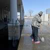 A shelter guest helps in clearing ice from outside the entry at Victory Temple in Beaumont, which opened to those in need of shelter from the storm Saturday and will remain open through Friday morning. Photo made Tuesday, February 16, 2021 Kim Brent/The Enterprise