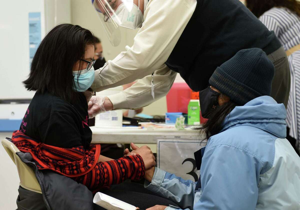 Roshni Modasi, left, is comforted by her mother, Namita, right, who held her hand while she received a COVID-19 vaccine injection during a vaccination clinic on Wednesday, Feb. 17, 2021, at the Center for Disability Services in Albany, N.Y. Albany County and Albany Medical Center, with the approval of the New York State Health Department, allocated 450 dosages of the Moderna COVID-19 vaccine to be administered to people who live in groups homes for persons with intellectual and developmental disabilities, as well as the workers who care for them. (Will Waldron/Times Union)