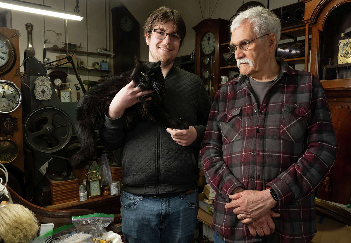 Max Nesbet and Dorian Clair pose for a photo with the shop cat, Mike, who is frequently seen in the window.