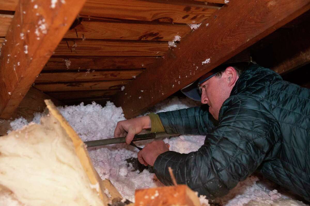 Nick Conway crawls into his attic and fixes a burst water pipe, due to the cold weather, with a repair tape Wednesday, Feb. 17, 2021, in Houston. Conway called his plumber but was told he was the 10th person on the line so he purchased the tape to fix the pipe himself.