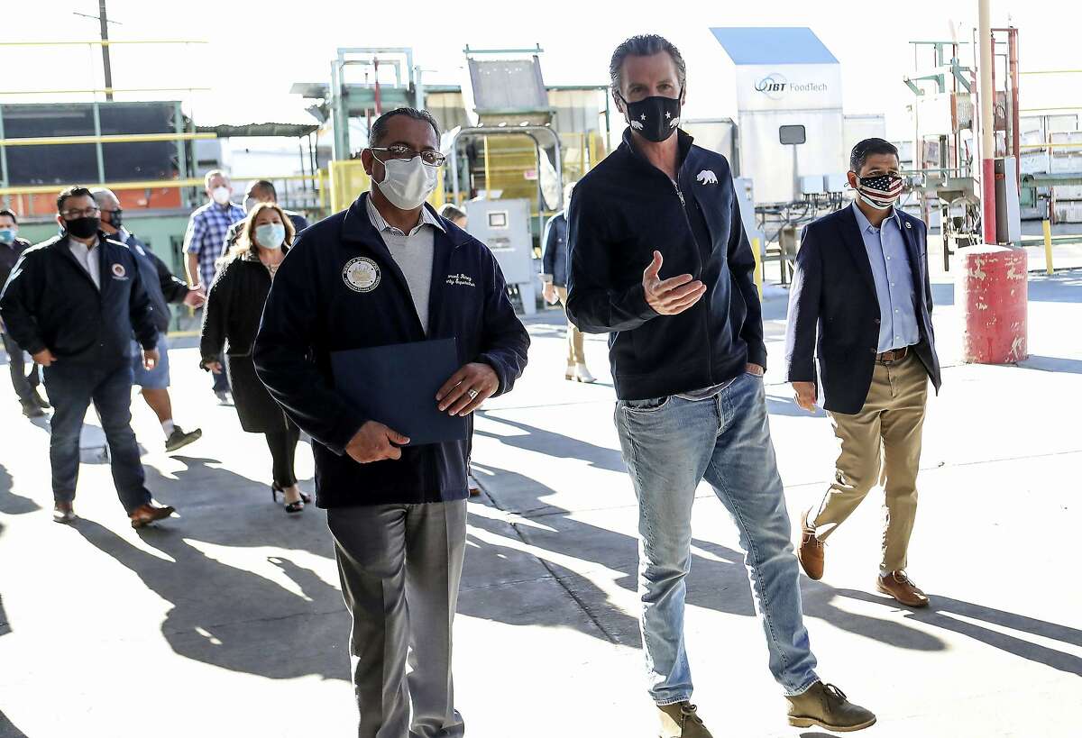 Gov. Gavin Newsom (right) walks with County Supervisor Manuel Perez before a news conference in Coachella (Riverside County). Newsom released details Wednesday on spending for small business grants, stimulus checks for individuals and housing for farmworkers infected by the coronavirus.