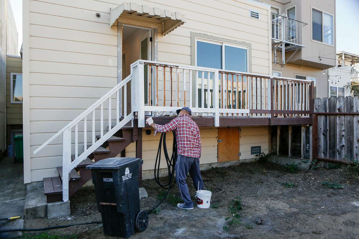 Phong Tang paints the outside banister of a single family home being renovated for sale in the Outer Sunset on Monday, October 26, 2020 in San Francisco, Calif.