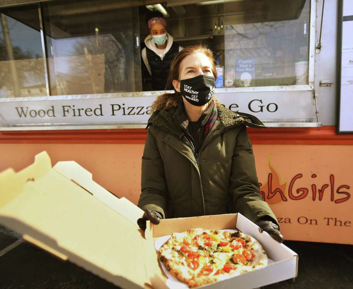 Lt. Gov. Susan Bysiewicz holds a brick oven pizza from small business owner Louise Joseph during a visit to her Dough Girls food truck outside the YMCA in Greenwich, Conn. on Wednesday, February 17, 2021. Bysiewicz was visiting with black female entrepreneurs across the state for Black History Month.