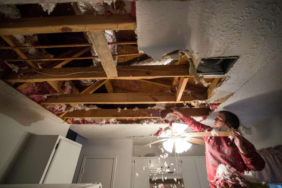 Hannah Siqueiros, clears insulation from a damaged ceiling after a broken pipe was repaired pipe above the kitchen in Michelle Toy's home Wednesday, Feb. 17, 2021 in Spring. Water from a damaged pipe above the kitchen caused the ceiling to collapse.