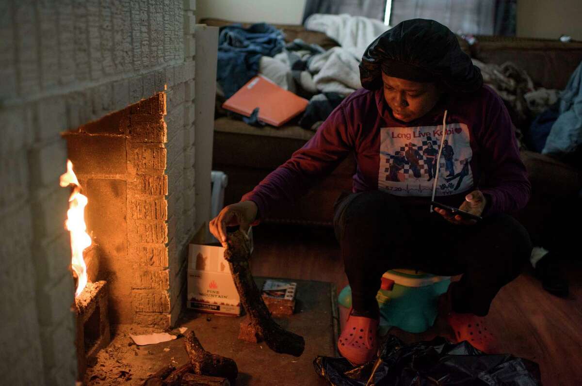 Linda McCoy throws wood onto a fire to heat in her home in Houston on Wednesday. Public safety officials warned about the dangers of carbon monoxide poisoning after emergency calls related to people using charcoal grills to try to heat their homes.