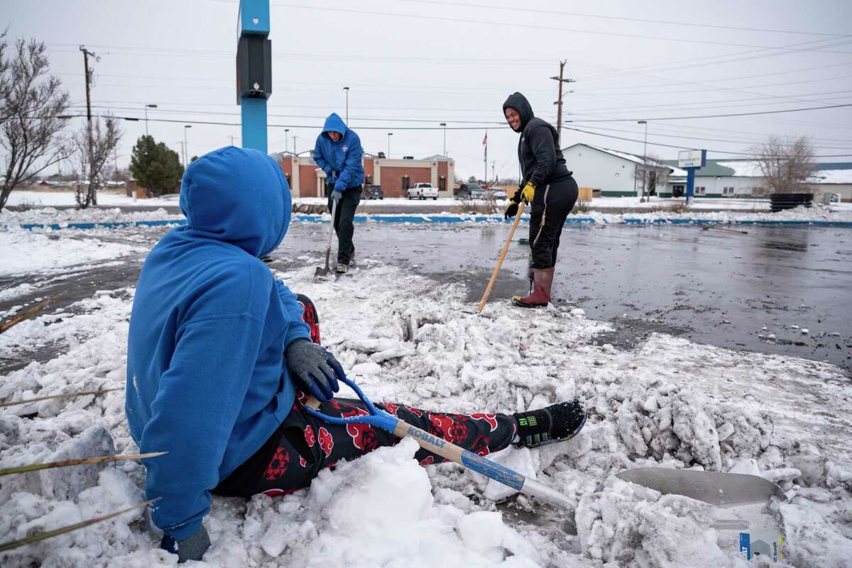 Mighty Wash employee Fuastino "Frosty" Calderon watches his coworkers shovel the car wash's driveway from atop a pile of snow after slipping on ice Wednesday, Feb. 17, 2021 in Odessa, Texas. Calderon and his coworkers shoveled snow at the car wash on Wednesday as a way to help pass the time and keep from being stuck inside as the Permian Basin begins to recover from the severe winter storm that passed through Texas. (Eli Hartman/Odessa American via AP)