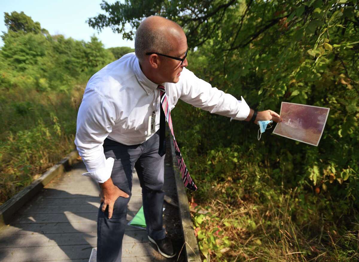 Hartford Detective Andrew Jacobson lines up an original crime scene photograph as he visits the scene of the 1982 unsolved murder of Sylvia Baker in Keney Park in Hartford, Conn. on Wednesday, September 16, 2020. Baker, who was strangled, was found on the shore of the nearby Keney Park Pond.