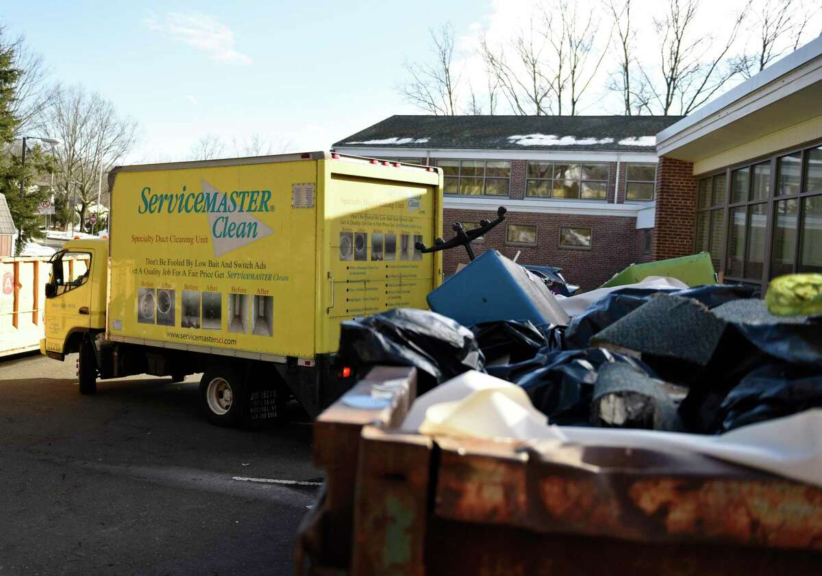 An HVAC truck pulls away as damaged items are piled into a dumpster outside North Mianus School in the Riverside section of Greenwich, Conn. Tuesday, Feb. 16, 2021.