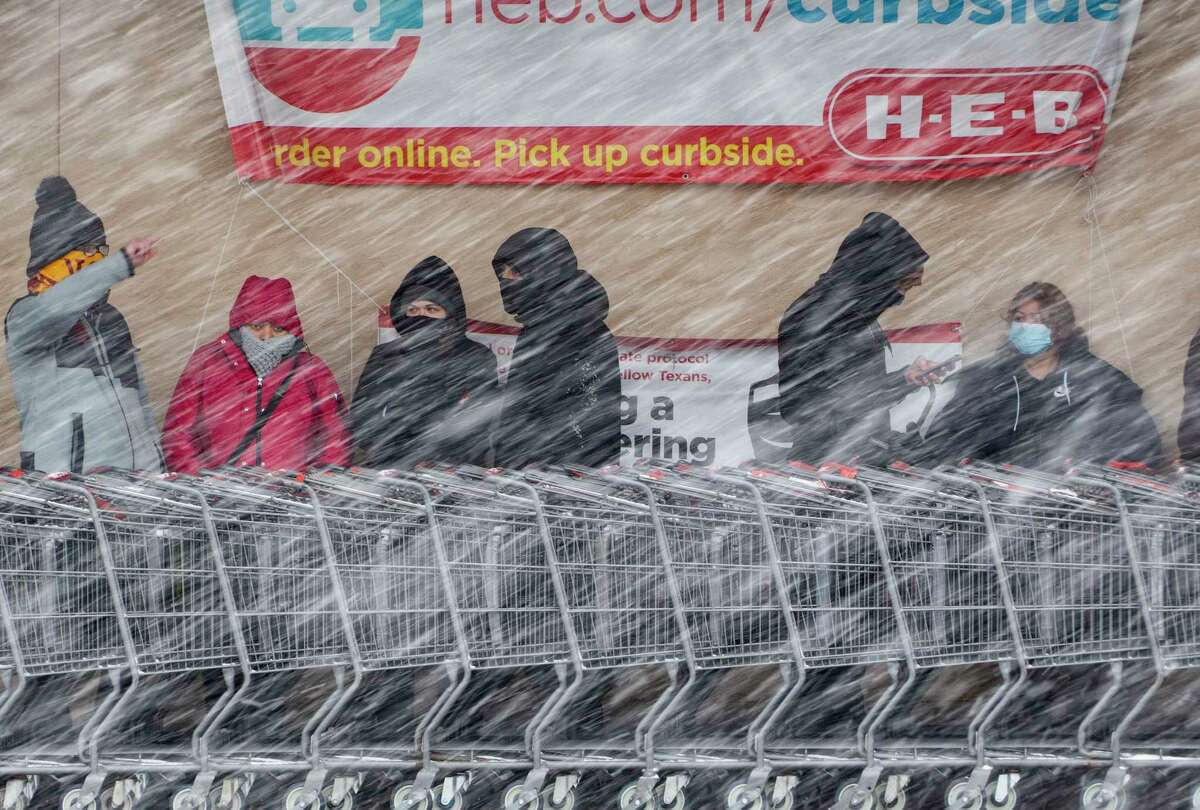 People wait in line to enter the H-E-B at West Avenue and Blanco Road as a brisk snow falls on Thursday morning, Feb. 18, 2021.