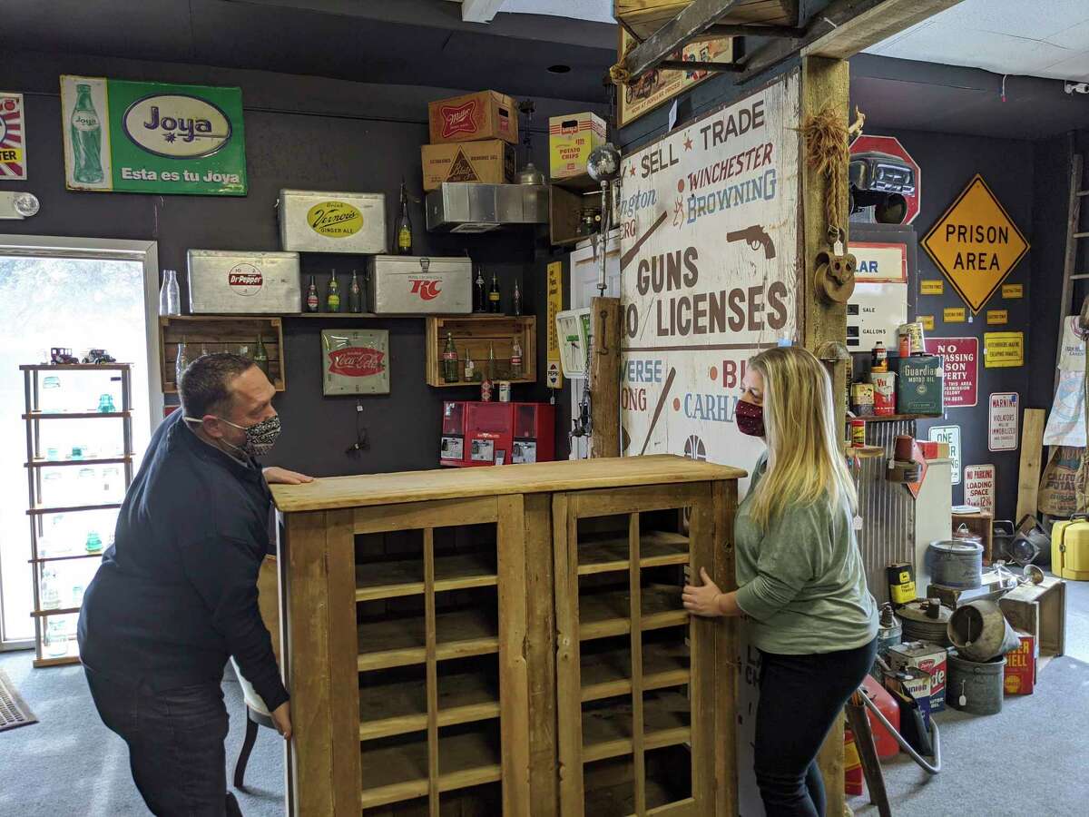 Beaverton Antique Mall vendor, Stan Lenneman, left, and owner Melissa Frye move a recently purchased pie safe. (Photo by Tereasa Nims, For the Daily News)