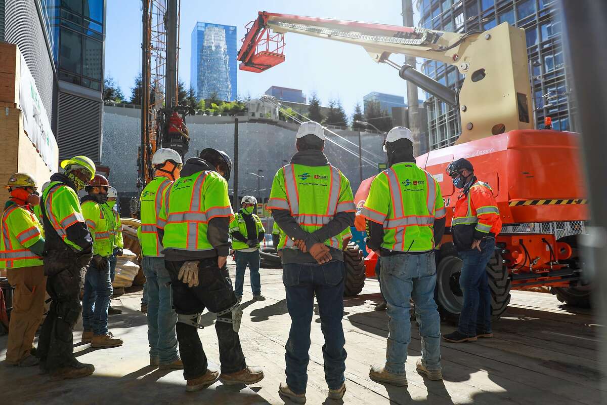 Construction crews gather for a meeting as they work at Millennium Tower on Mission Street.