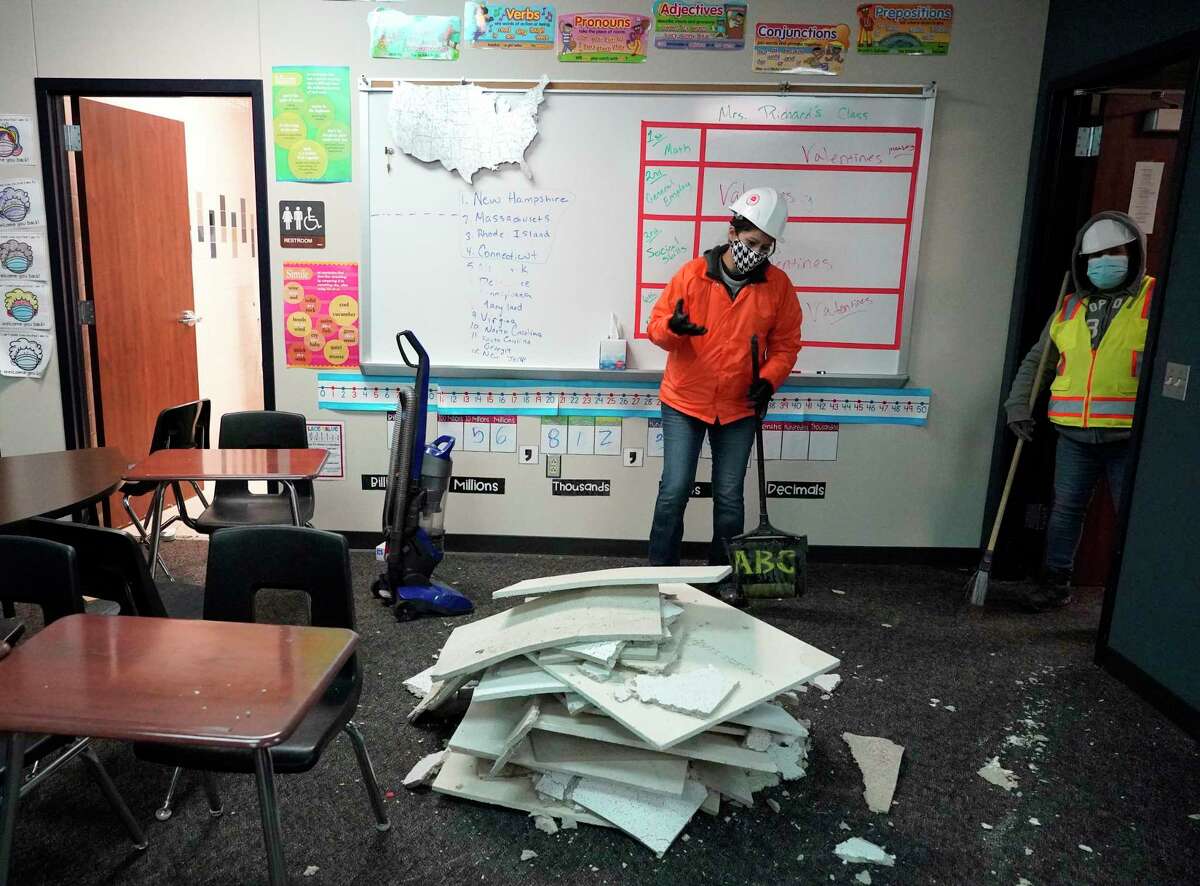 Workers clean up damage in a classroom from broken water pipes in the fire suppression system at Tomball Memorial High School Thursday, Feb. 18, 2021 in Tomball.