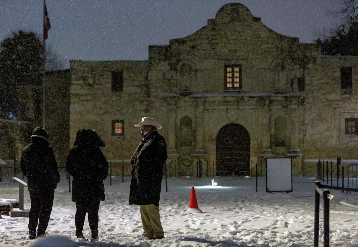 An Alamo security guard talks early Monday morning, Feb. 15, 2021 with people coming to look at the blanket of snow covering the Alamo. The National Weather Service reported Tuesday morning San Antonio and surrounding areas saw 3-5 inches of snow and some pockets of the forecast area saw 6-7 inches of snow. The Electric Reliability Council of Texas (ERCOT) has also declared the highest level of energy emergency and is requiring rolling blackouts throughout Texas. The National Weather Service reports the areas temperatures are the coldest since 1989.